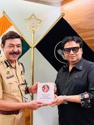 Ashutosh Dumbare in Maharashtra Police uniform receiving a publication from a visitor at his office.