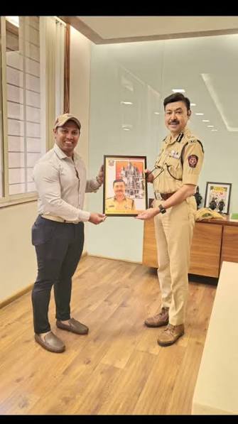 Ashutosh Dumbare in Maharashtra Police uniform receiving a framed photograph from a visitor at his office.