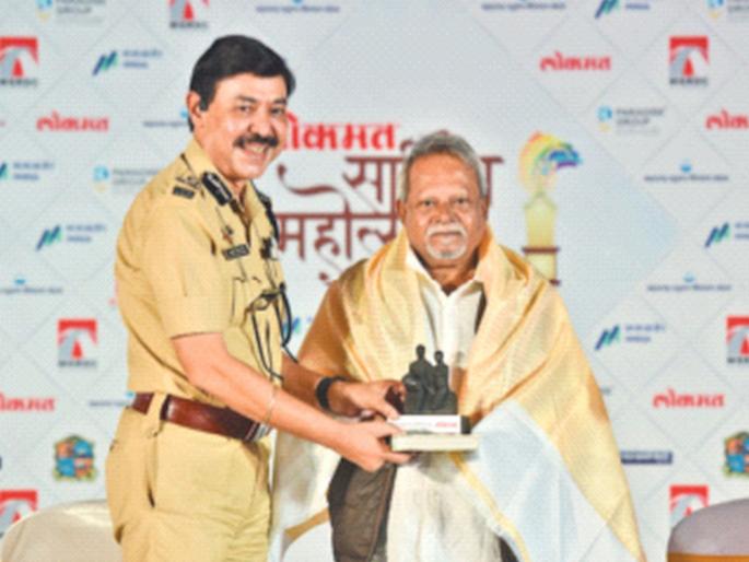 Ashutosh Dumbare in Maharashtra Police uniform presenting a memento to a guest on stage at a Lokmat literary festival event.
